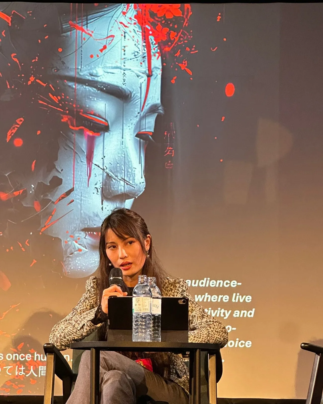 Alexandra Huang-Kokina speaks on a panel in front of the key art from Ghost of the AI Empire